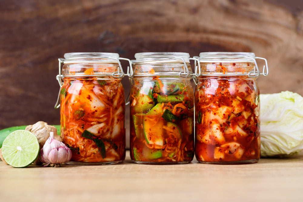 fermented foods and gut health. kimchi cabbage, cucumber and radish fermenting in a jar