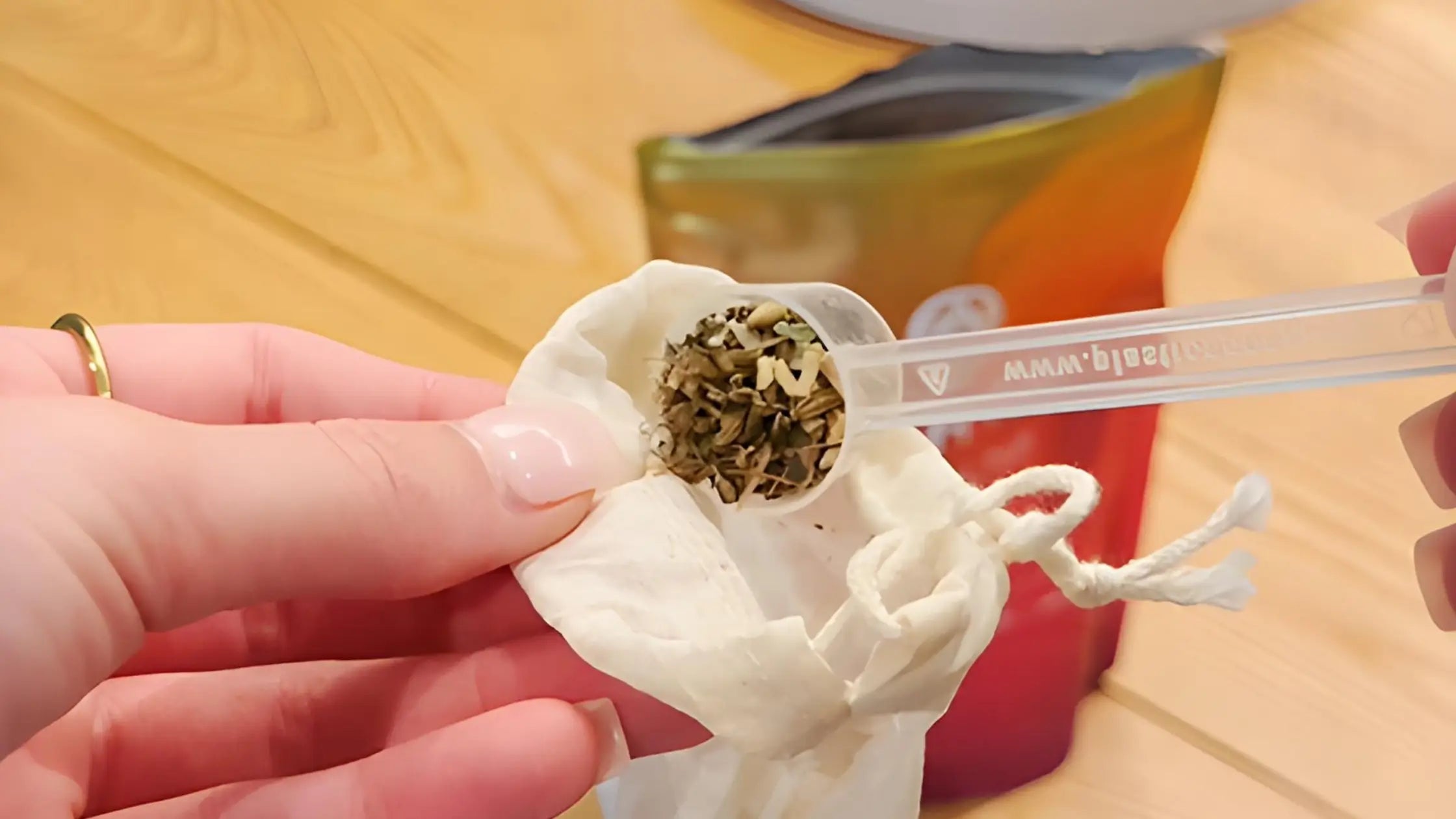 lady putting cosmic hue tea into reusable organic cotton tea bag ready to brew tea
