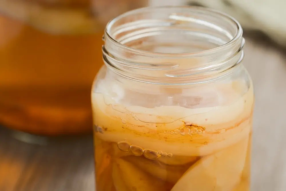 Homemade black tea kombucha in glass jar with lots of scoby, a healthy fermented probiotic drink