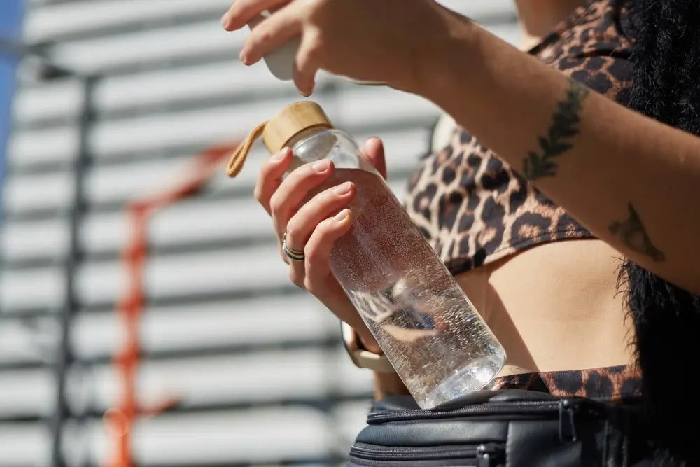 Woman holding reusable glass bottle with filtered water