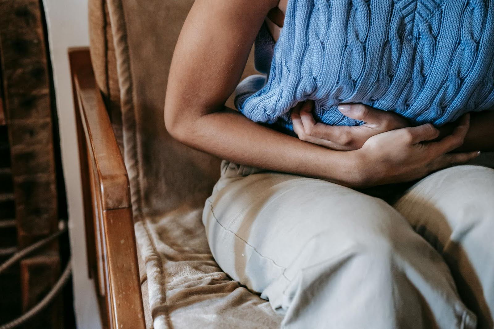 person on a chair learning forward holding their stomach in pain