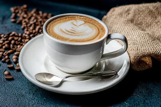 coffee in a white cup with spoon on table with coffee beans and bag