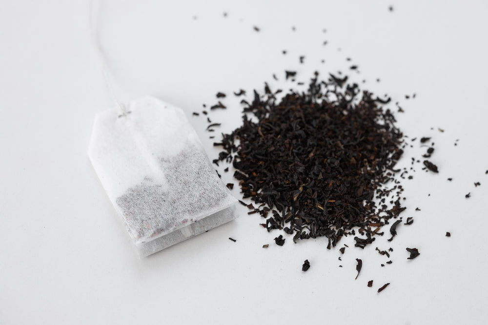 loose tea vs tea bags - Tea bag on a white background. Tea bag on a pile of loose tea. Fast and convenient way to brew tea
