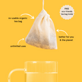 Re-usable organic tea bag hovering above clear glass of hot water graphic.